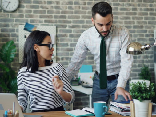 a man and a woman standing in front of a laptop