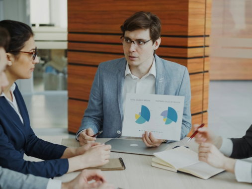Man presenting charts to colleagues in a meeting.